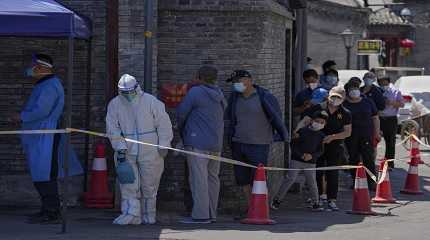 A worker in protective suit sprays disinfectant as residents