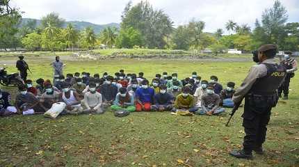 Indonesian police officers watch a group of ethnic Rohingya