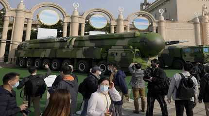 Visitors tour past military vehicles carrying the Dong Feng