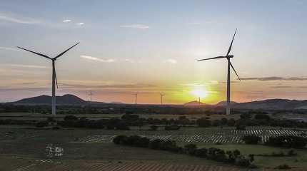 sun sets behind a windmill farm 