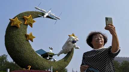 woman takes a souvenir photo with a floral decoration