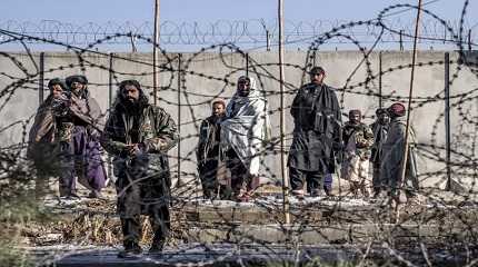 Taliban fighters check the site of an explosion