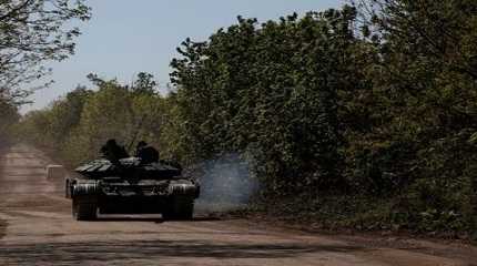 Ukrainian servicemen ride atop of a tank on a road