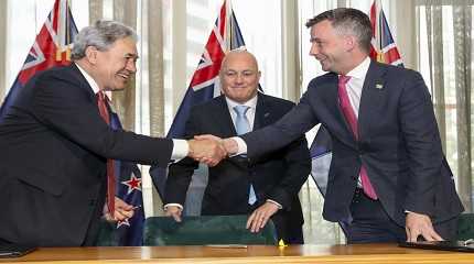 Christopher Luxon watches, as Winston Peters and David Seymour shake hands