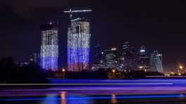 A high-rise apartment block under construction illuminated in the colours of the Russian flag