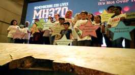 Family members  with a debris of the missing Malaysia Airlines flight MH370