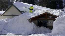 worker clears snow off the roof