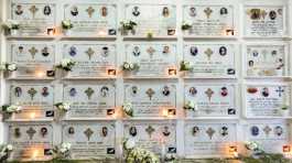 Candles are lit on a memorial wall