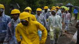 rescuers walk towards the site of a landslide