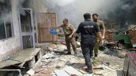 police officer pours water into a burning house