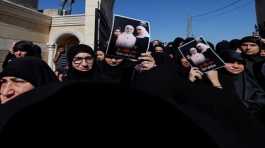 Mourners hold photographs